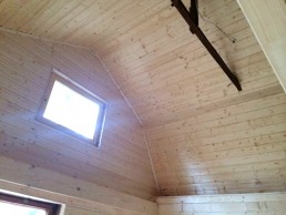Ein Raum mit einer Holzdecke und einem Fenster in Holzrahmenbauweise.