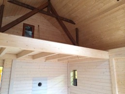Das Innere einer Holzhütte mit Holzbalken und Dach.