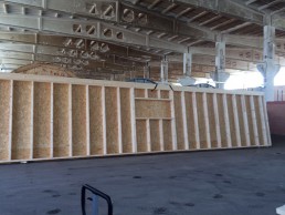 Ein Holzrahmenbau-Gebäude wird in einer Lagerhalle errichtet.