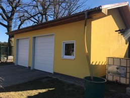 Ein gelbes Haus mit angeschlossener Garage im Bau mit Holzrahmen