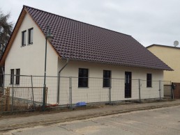 Beschreibung: Ein Haus mit einem braunen Dach und einem Zaun. (Hausbau)