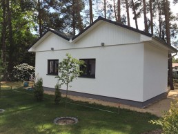 Ein kleines weißes Haus, umgeben von dichtem Wald.