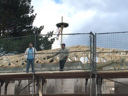 Zwei Männer arbeiten auf einem Gerüst stehend an der Sanierung und dem Neubau eines Dachstuhls mit Abbund-Technik.