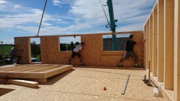 Eine Gruppe Männer arbeitet für ein Projekt an einem Holzhaus.